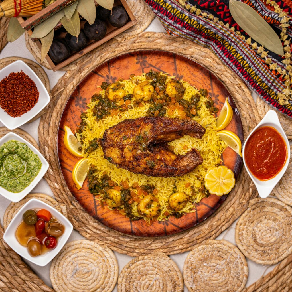 Colorful top-view shot of spiced fish and rice with various sauces and garnishes.